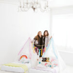 Ashley Minor and Erica Haynes pose between two glamping tents