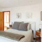 Bedroom-with-a-white-bed-and-grey-oversized-pillows-and-a-cozy-blanket-at-the-foot-of-the-bed