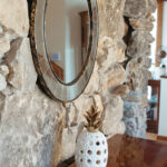Mirror-on-a-rock-wall-and-vase-on-a-wooden-cabinet