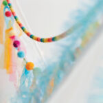 Rainbow pom pom garlands drape between two tents