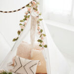 White glamping tent with pale pink florals draped over the opening