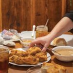 A-hand-reaches-for-fried-chicken-in-the-middle-of-a-full-dining-table