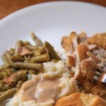 Close-up-of-a-full-plate-of-fried-chicken-green-beans-mashed-potatoes-and-gravy