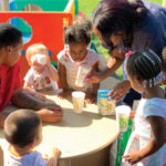 Ouside-Fun-with-kiddos-gathered-around-a-table-looking-at-seeds