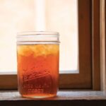 mason-jar-filled-with-iced-tea-sitting-on-the-ledge-of-a-window-sill