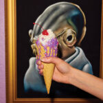 Hand-holding-ice-cream-cone-in-front-of-artwork-on-the-wall-of-Sparkys