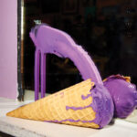 Ice-cream-cone-sitting-on-ledge-in-front-of-mirror-a-purple-swoosh-of-ice-cream-on-the-mirror