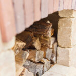 artistic-shot-of-wood-stacked-underneath-an-archway-of-bricks