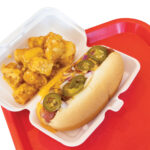 Cheesey-Tots-and-a-chili-dog-in-a-to-go-container-on-a-red-tray