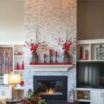 wide-shot-of-fireplace-and-mantel-decorated-in-red-ornament-garland,-red-candles-and-red-berries