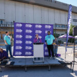 Mayor-Barbara-Buffalo-standing-at-the-lectern-on-the-stage-giving-a-speech-in-front-of-the-walk-to-end-alzheimers-backdrop