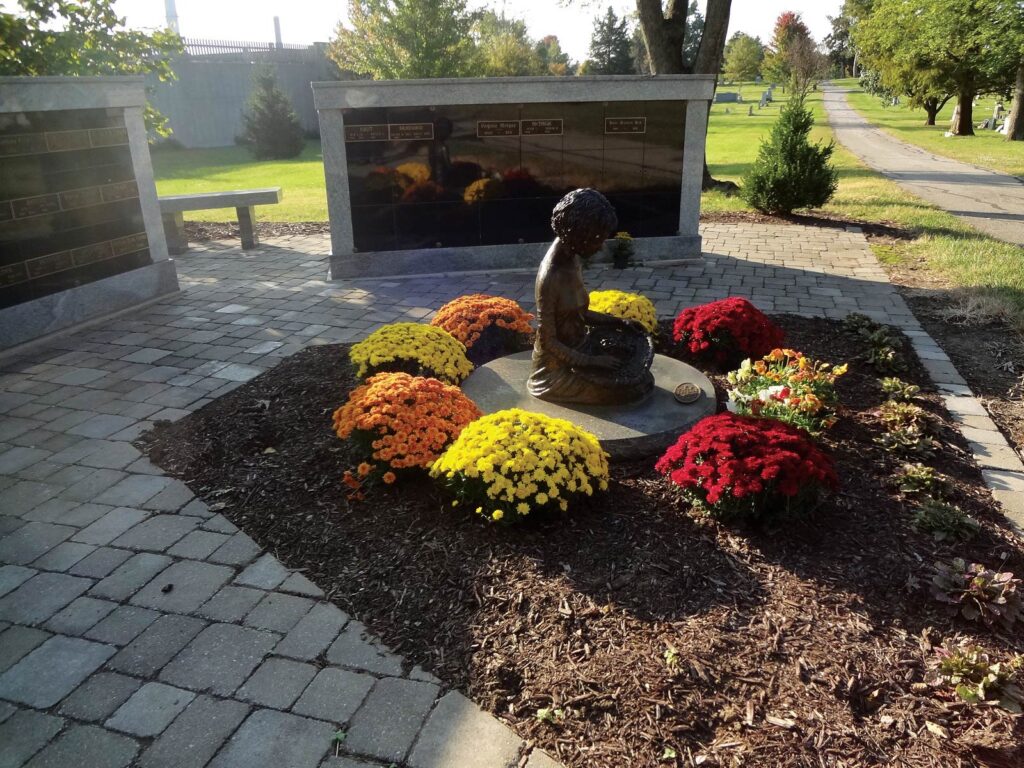 Statue in cemetery surrounded by flowers. 