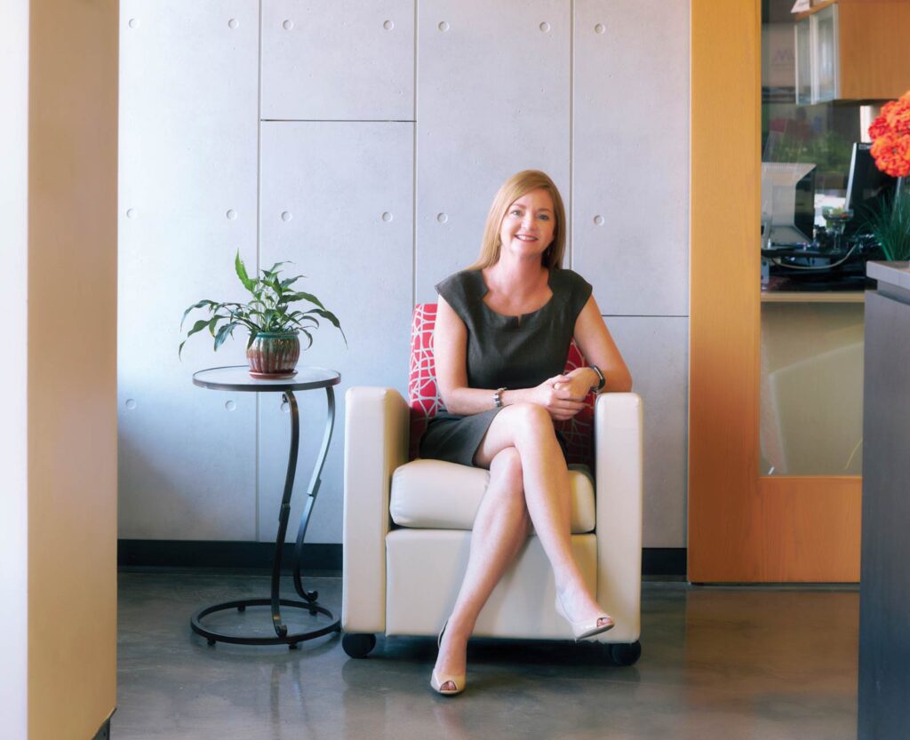 Stacey Button sits in an armchair in the REDI office