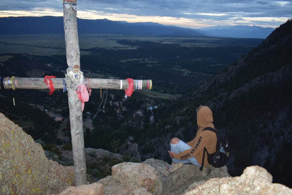 Student next to cross in the mountains