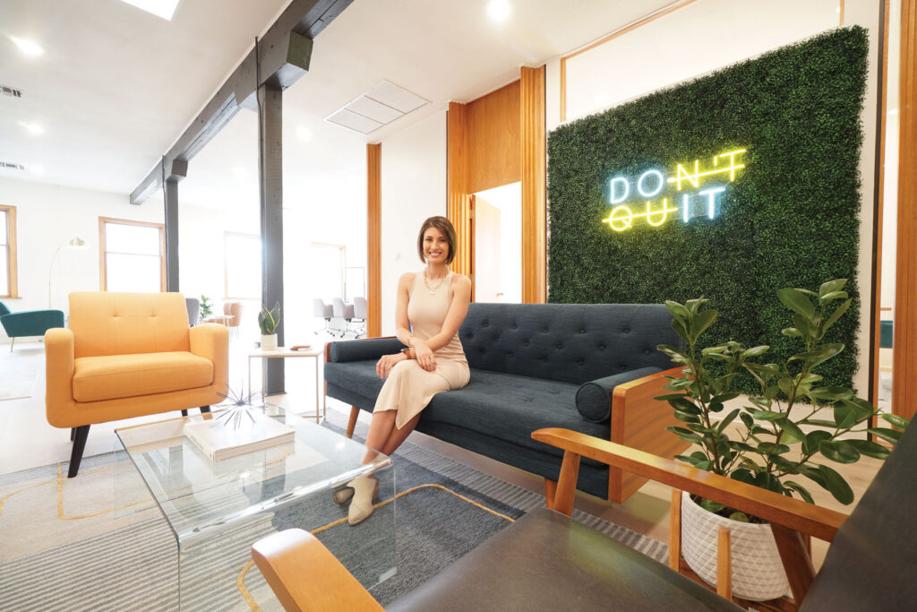 Megan Walters poses in front of a lit sign that reads Don't Quit.