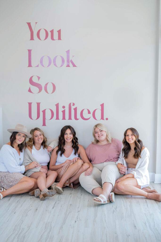 Women of Uplifted Salon pose in front of interior wall