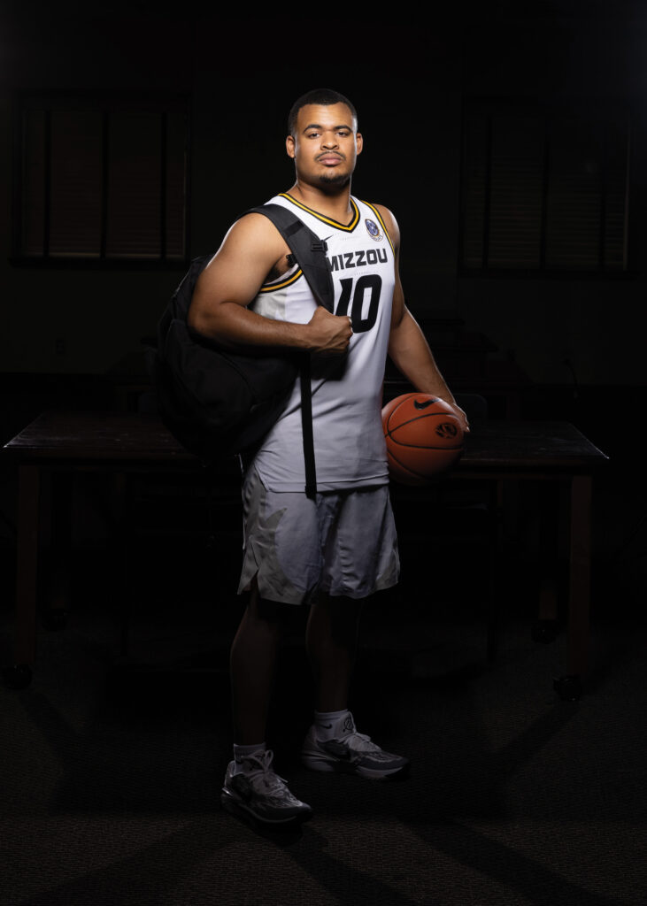 Mizzou student-athlete Nick Honor, a guard for the Tiger basketball team, stands with a backpack while also holding a basketball.