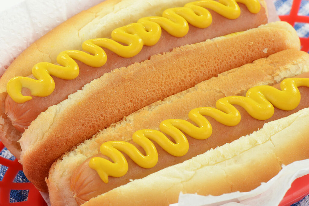 Two hot dogs with mustard, on buns.