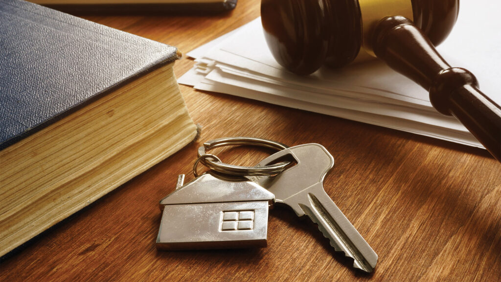 Judges gavel lays on desk next to keychain with a home key