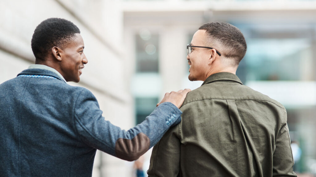 Man smiling at friend with hand on shoulder