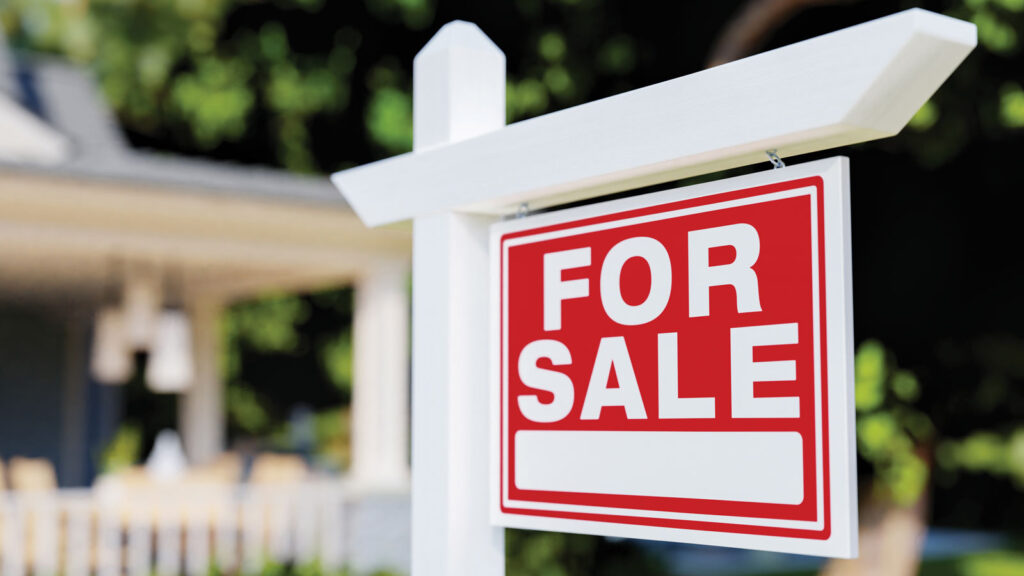 Red For Sale sign hanging on wooden post