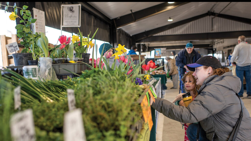 Adult and child browse seasonal produce variety at Columbia Farmers Market