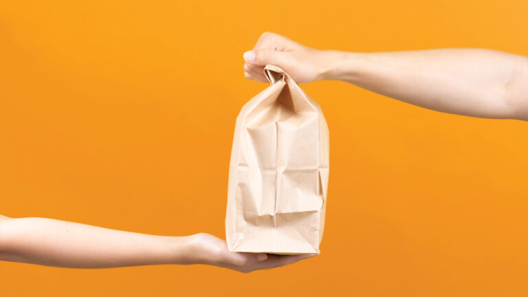 People Passing Off A Bag Of Delivery Food