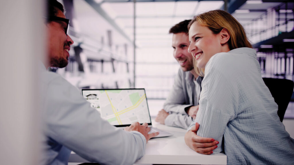 Featured Couple And Realtor Looking At House Listing On Map