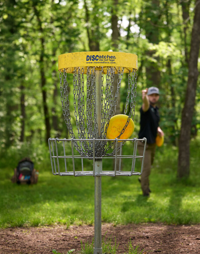 Pro Am Disc Golfer Chris Baker Throws A Disc Into Basket At Harmony Bends