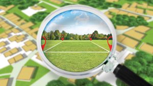 Magnifying glass showing a zoomed in shot of a plot of land with markers for new development.