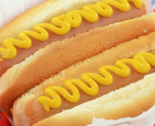Two hot dogs with mustard, on buns.