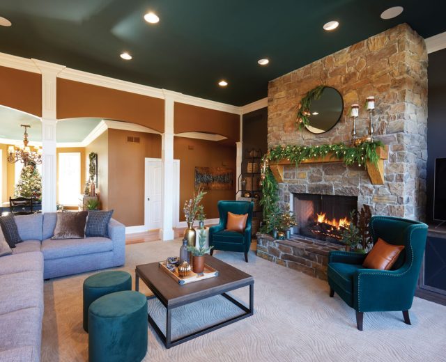 Wide-shot-of-the-living-room-sofa-green-chairs-fireplace-and-adjoining-room-in-the-back