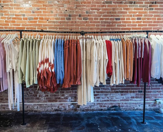 a-long-rack-of-clothes-hanging-in-front-of-a-brick-wall