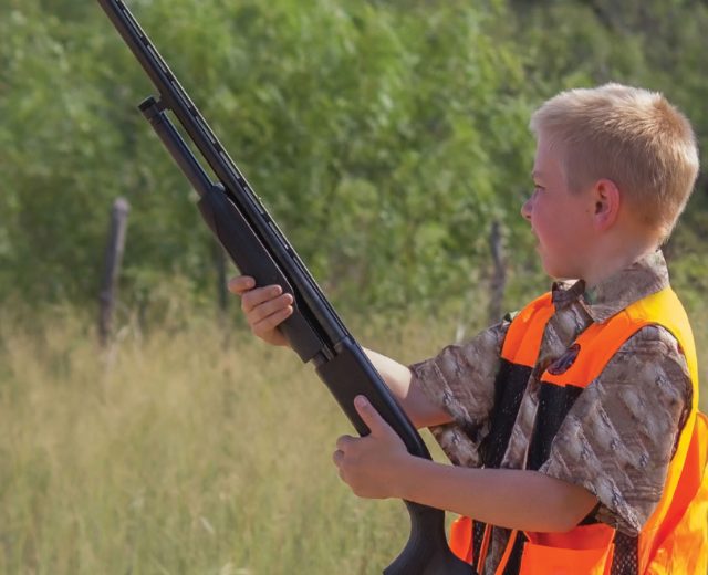 A young hunter patiently waiting using appropriate safety precautions