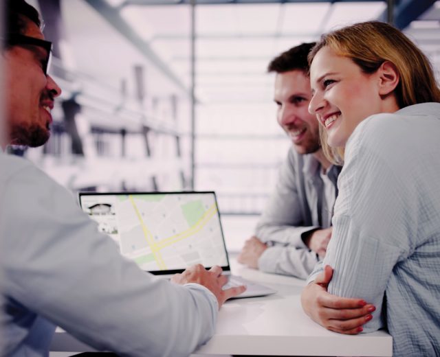 Featured Couple And Realtor Looking At House Listing On Map