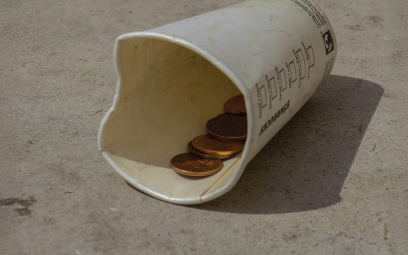 Disposable Cup On The Ground With A Few Coins Inside