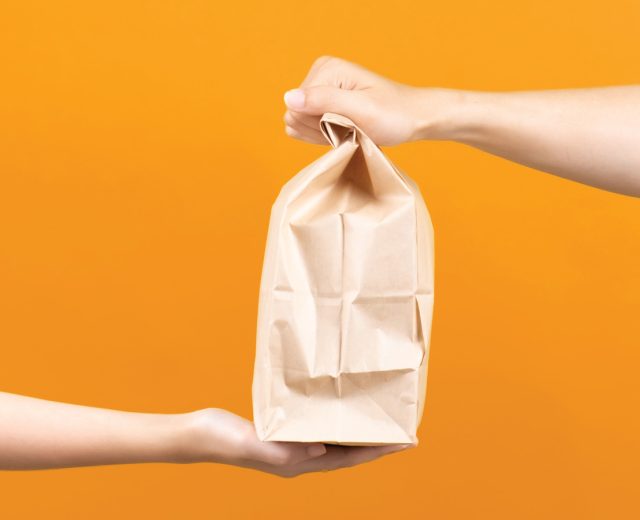 People Passing Off A Bag Of Delivery Food