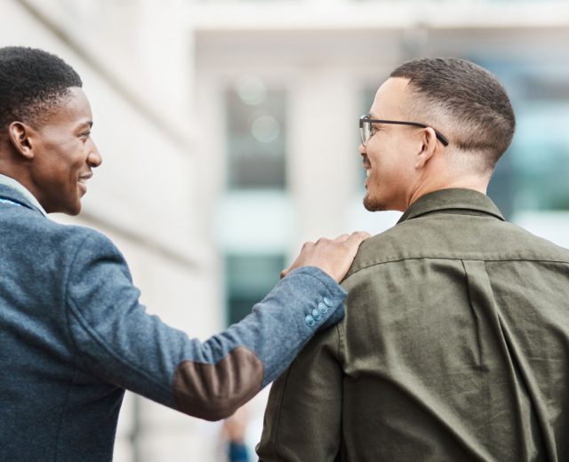 Man smiling at friend with hand on shoulder