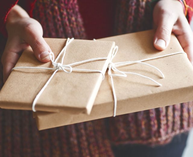 person-holding-books-wrapped-in-brown-paper-tied-with-string